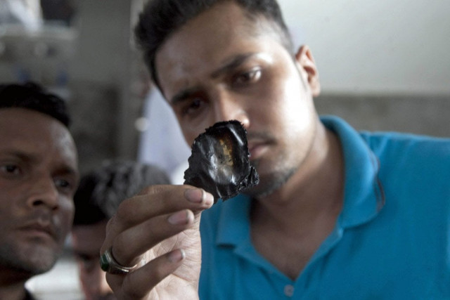 a man showing a burned identity card of one the victims who died in the cold storage facility of karachi airport photo express mohammad azeem a man showing a burned identity card of one the victims who died in the cold storage facility of karachi airport photo express mohammad azeem