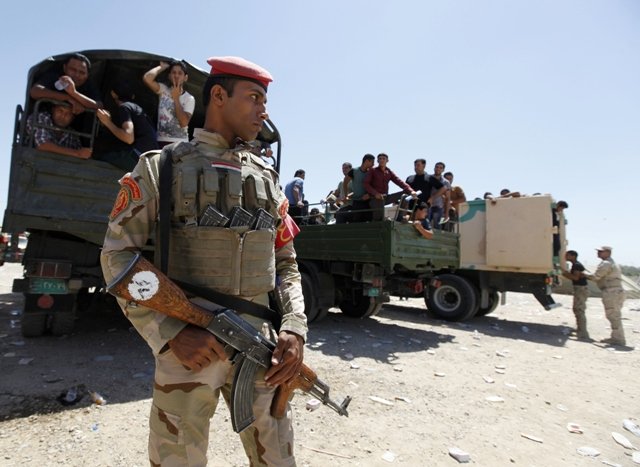 a member of iraqi security forces stands guard in front of volunteers in baghdad who have joined the iraqi army to fight against the predominantly sunni militants from the radical islamic state of iraq and the levant who have taken over mosul and other northern provinces photo reuters