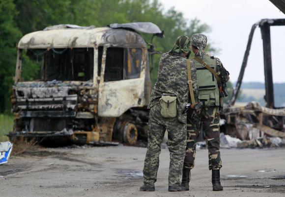 pro russian separatists stand guard at a checkpoint near a burnt truck outside luhansk june 18 2014 photo reuters