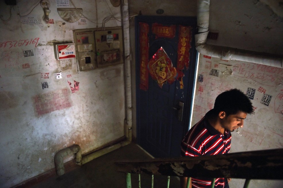 this photo taken on june 18 2014 shows a pakistani refugee as he walks past chinese decorations in the stairwell of his apartment building in sanhe in china 039 s hebei province east of beijing photo afp