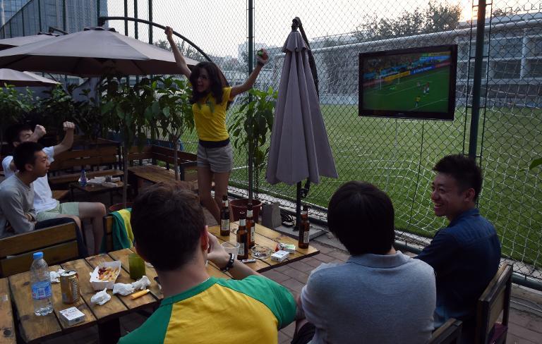 chinese and brazilian football fans watch the opening match of the world cup live on a tv screen in a beijing park on june 13 2014 photo afp