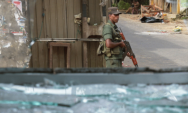 a sri lankan soldier stands guard by a roadside following clashes between muslims and an extremist buddhist group in the town of alutgama on june 17 2014 photo afp a sri lankan soldier stands guard by a roadside following clashes between muslims and an extremist buddhist group in the town of alutgama on june 17 2014 photo afp