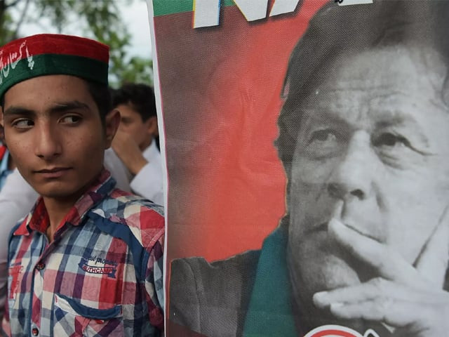 a supporter of imran khan s pti party looks at the party leader 039 s poster in islamabad july 2018 photo afp