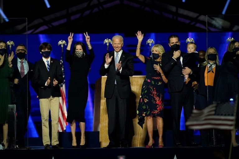 us president elect joe biden c with his wife jill biden and members of their family salute the crowd on stage after delivering remarks in wilmington delaware on november 7 2020 afp