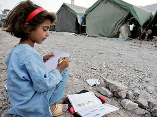 a pakistani kashmiri girl a survivor of the 08 october 2005 earthquake studies outside her makeshift tent in muzaffarabad photo afp
