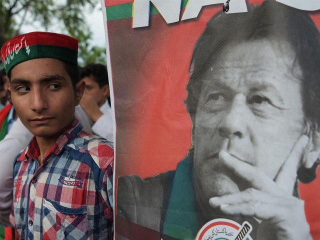 a pti supporter stands next to a poster of imran khan in islamabad photo afp