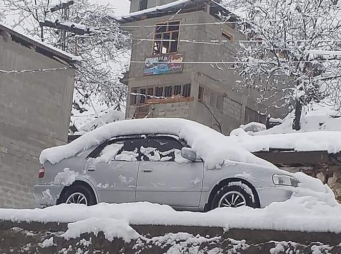 a car covered in snow appear stuck in what seems to be at least two feet of snow on a street in lower dir photo express