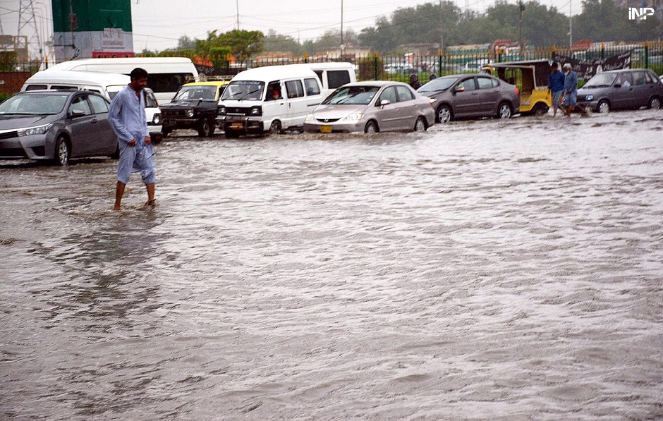 A view of a man walking in the rain at Akhter Colony. PHOTO: APP