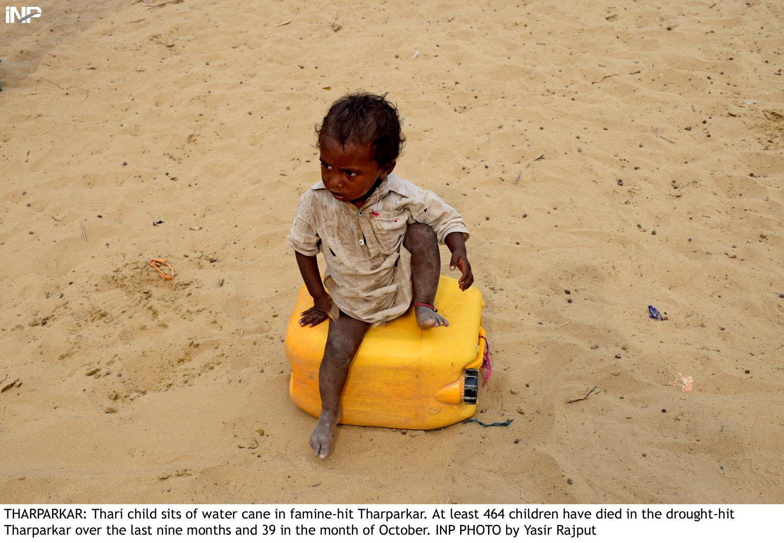a child sits on a water can in tharparkar photo inp file