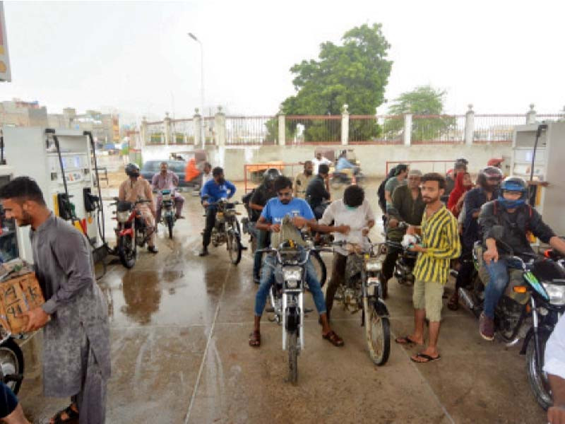 motorcyclists take shelter at a filling station on korangi road from heavy rain that lashed the city on saturday photo jalal qureshi express