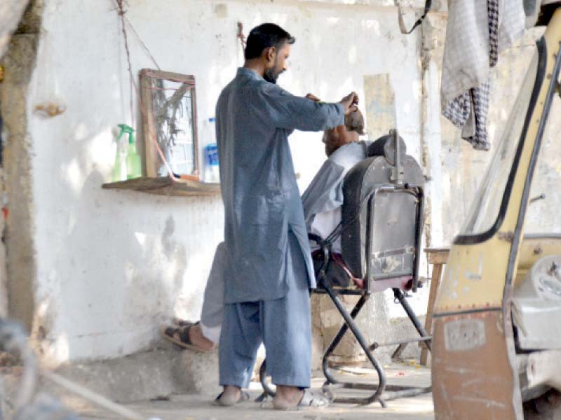 a barber gives an old fashioned street side haircut to a customer in the city photo express