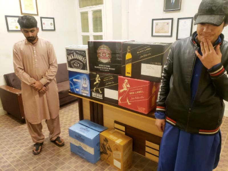 arrested bootleggers with the crates of liquor police recovered from the trunk of their car photo express