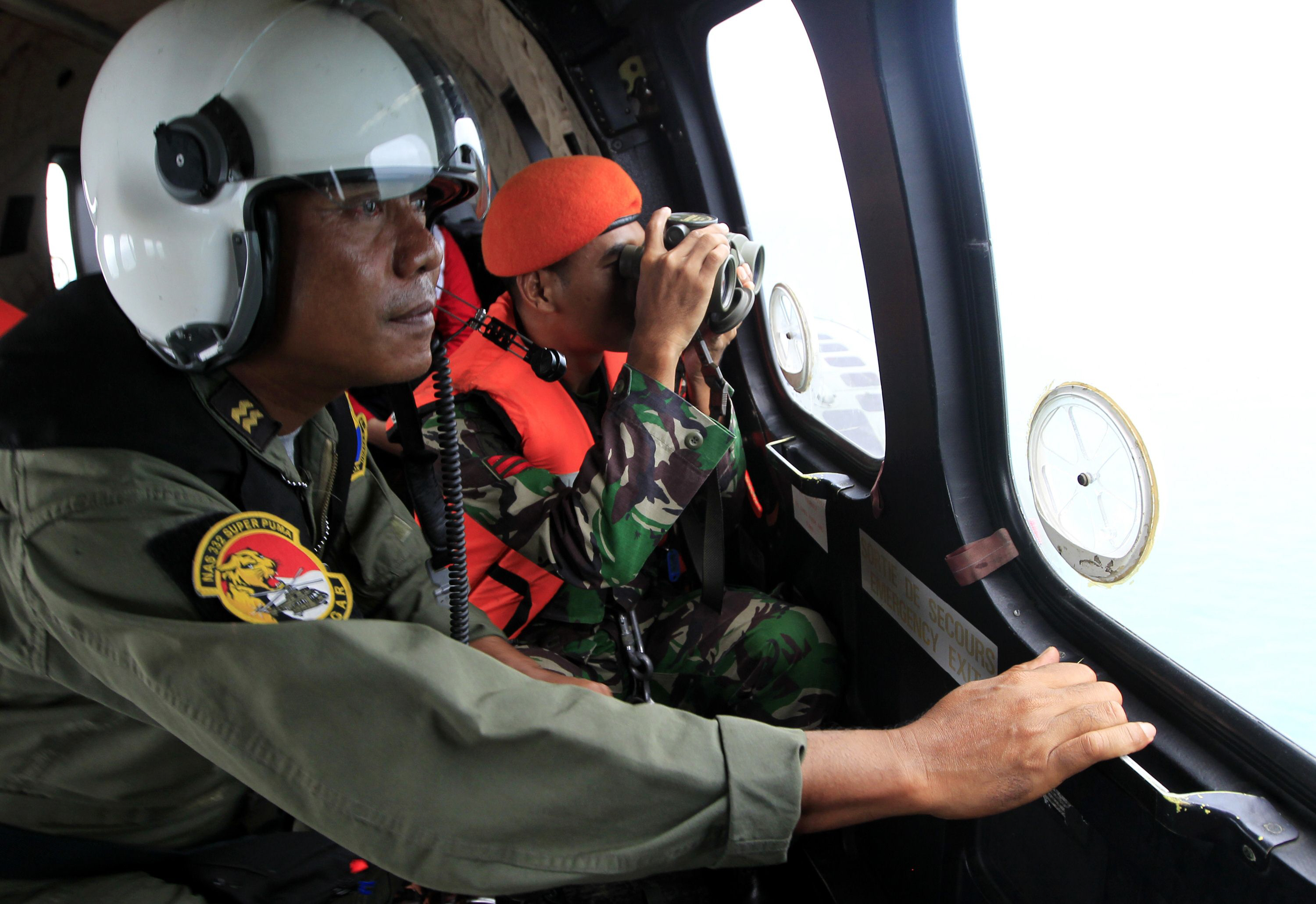 indonesian crew members observe the surface of the sea during the search for airasia flight qz8501 on board an aircraft over the java sea on january 1 2015 photo afp