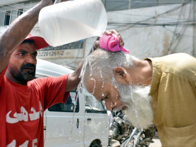 an edhi volunteer provides an elderly passerby relief from the heat near merewether tower left while a traffic policeman uses an umbrella to shade himself from the blazing sun right photos jalal qureshi express