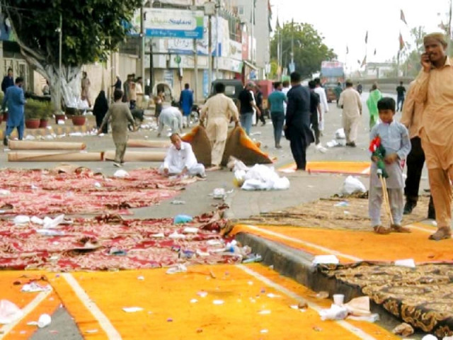 workers roll up rugs laid out for the pti sit in at numaish chowrangi on thursday morning photo express workers roll up rugs laid out for the pti sit in at numaish chowrangi on thursday morning photo express