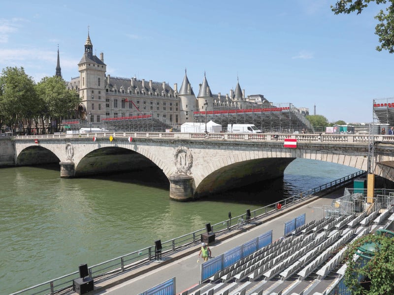 a worker walks past stands set up for spectators in front of the conciergerie in paris ahead of the opening ceremony of the olympic games photo afp