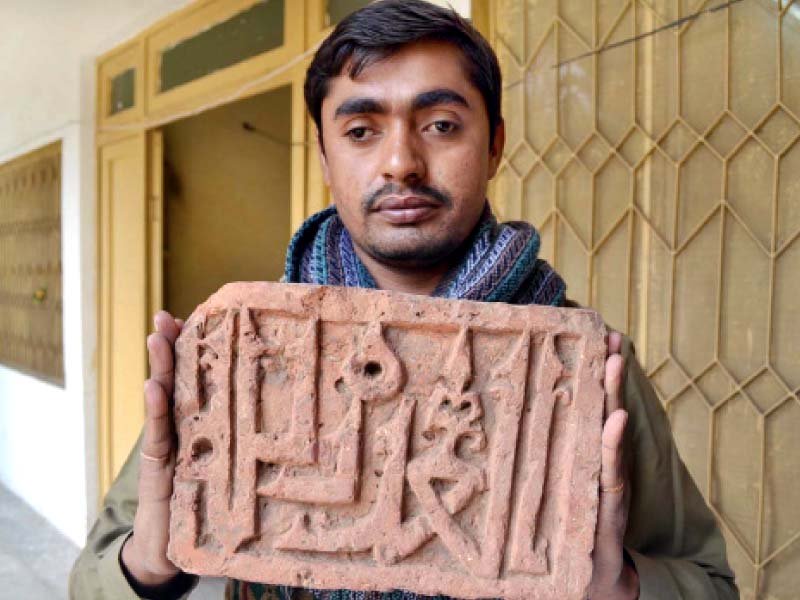 a man displays a teracotta slab found in the excavation at the mausoleum photo app