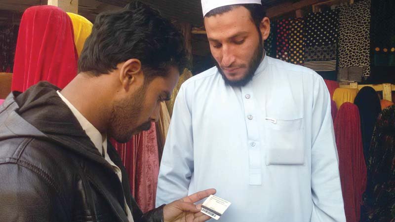 an official checks the identification card of an afghan national photo fazal khaliq express