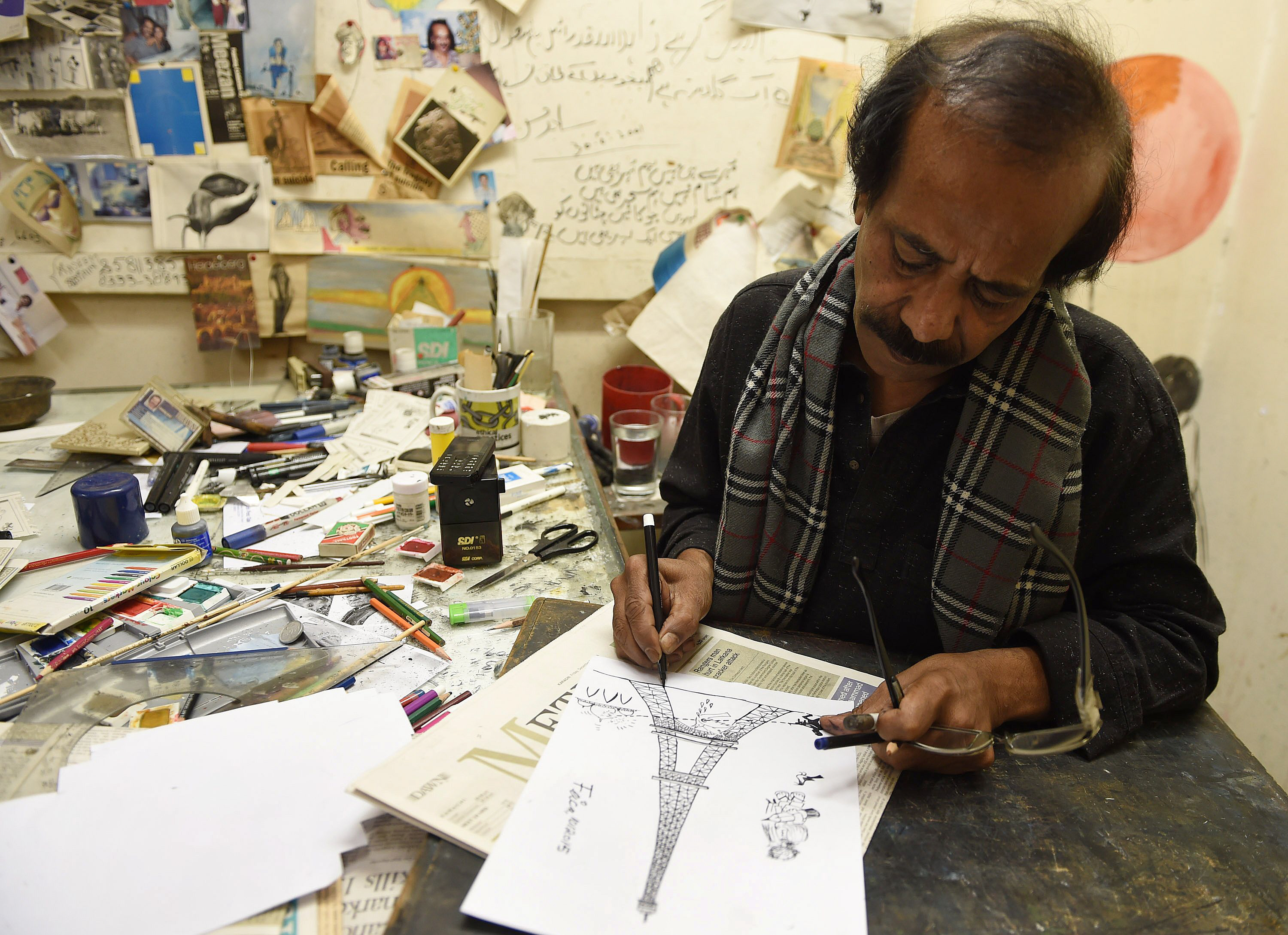 in this photograph taken on january 9 2015 pakistani cartoonist rafique ahmad alias quot feica quot draws at his office in karachi photo afp