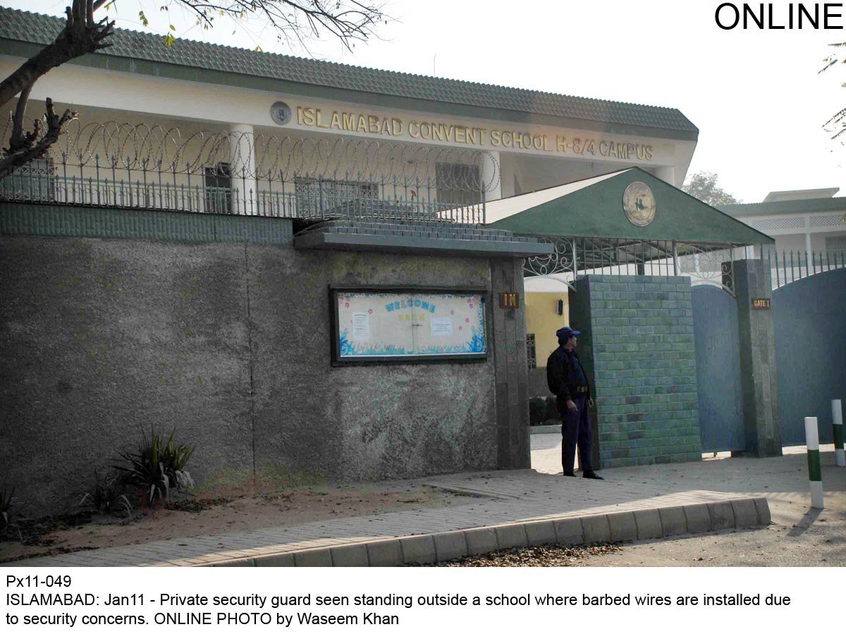 a security guard stands alert at the entrance of a school in islamabad which has added barbed fencing on it walls photo online