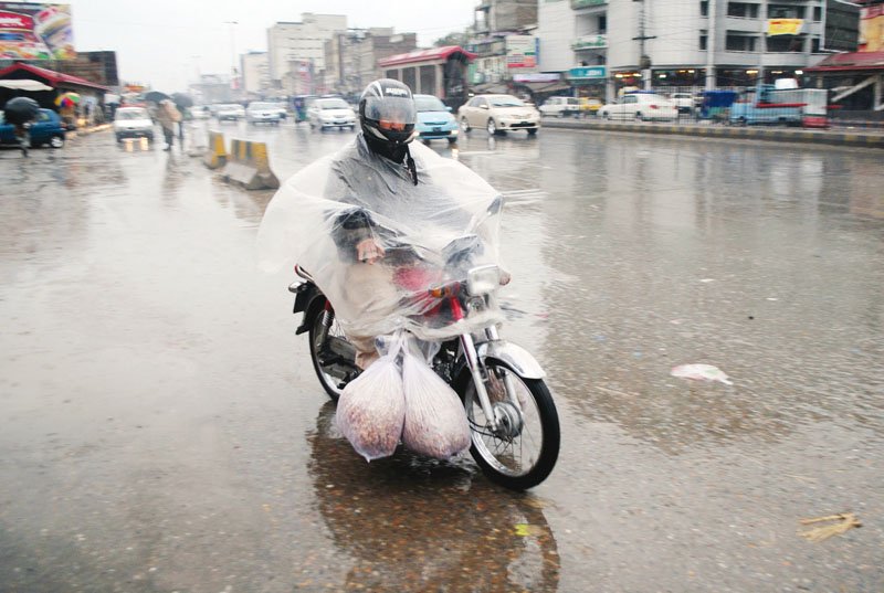 a man drives his motorcycle through the rain on gt road photo muhammad iqbal express