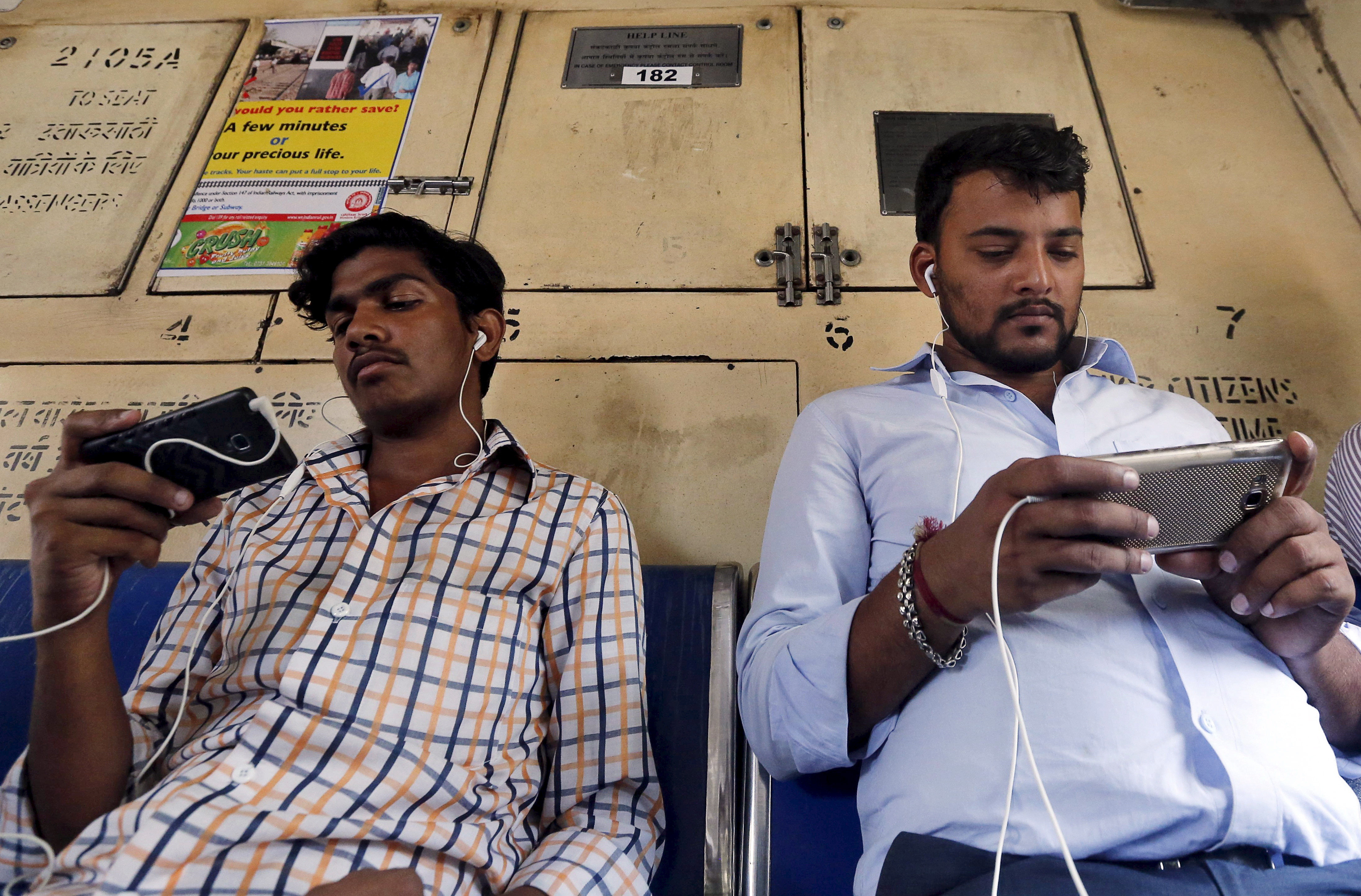 commuters watch videos on their mobile phones as they travel in a suburban train in mumbai india april 2 2016 photo reuters