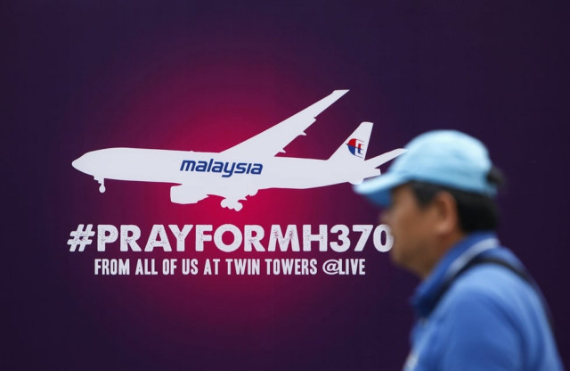 a tourist walks past a signboard saying quot pray for mh370 quot in front of the kuala lumpur city center klcc march 14 2014 photo reuters