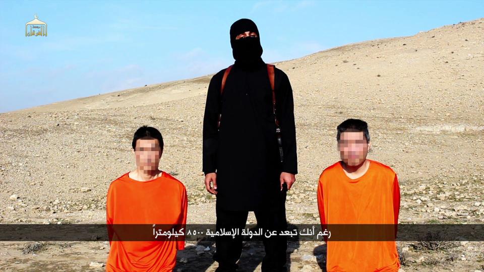image grab taken off a video on january 20 2015 reportedly released by the islamic state allegedly shows japanese hostages kenji goto l and haruna yukawa r with a black clad militant brandishing a knife at an undisclosed location photo afp