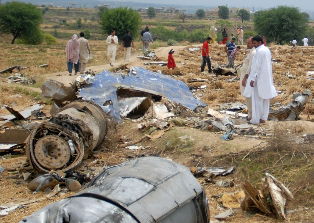 people stand amid the debris of bhoja air boeing 737 crash on the outskirts of islamabad on april 25 2012 photo afp