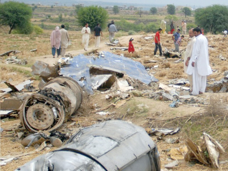 people stand amid the debris of bhoja air boeing 737 crash on the outskirts of islamabad on april 25 2012 photo afp file