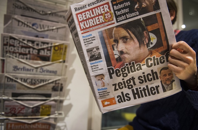 a woman reads a newspape carrying a picture of pegida leader lutz bachmann allegedly posing as hitler in berlin photo afp