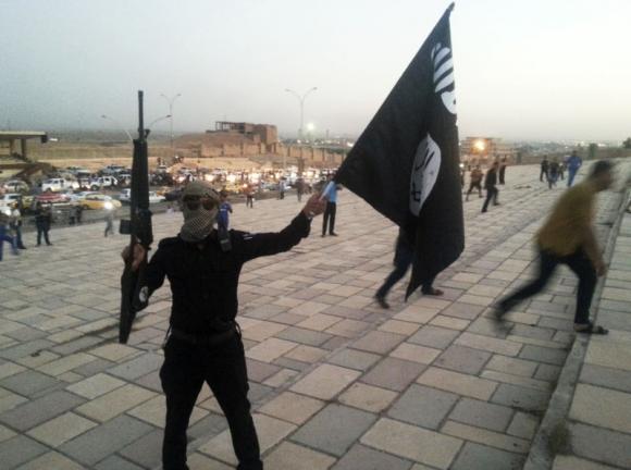 a fighter of the islamic state of iraq and the levant isil holds an isil flag and a weapon on a street in the city of mosul june 23 2014 photo reuters