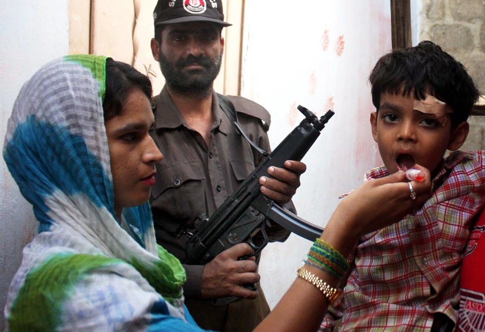 a file photo of karachi policeman on guard as a polio worker administers vaccination photo online