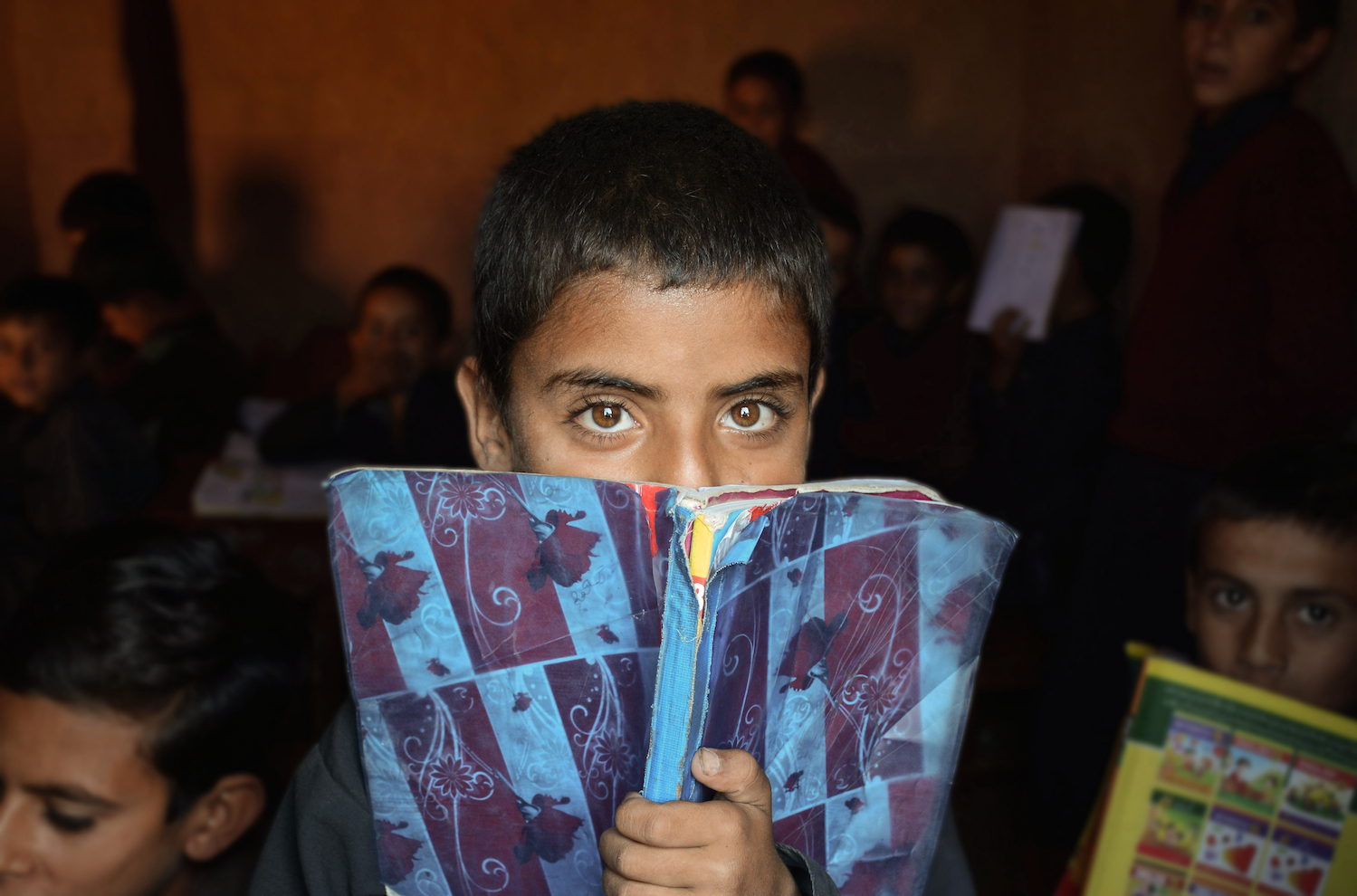 six year old mehran peeks out of a window from his one room makeshift school in the afghan slum on the outskirts of islamabad photo huma choudhary