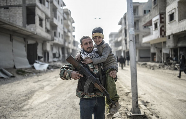 a kurdish fighter holds his child in the center of the syrian border town of kobane known as ain al arab on january 28 2015 photo afp a kurdish fighter holds his child in the center of the syrian border town of kobane known as ain al arab on january 28 2015 photo afp