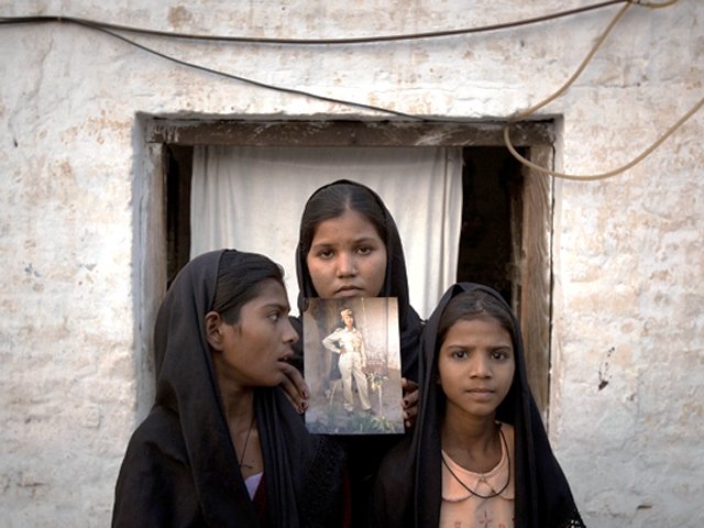 the daughters of asia bibi with an image of their mother standing outside their residence in sheikhupura on november 13 2010 photo reuters