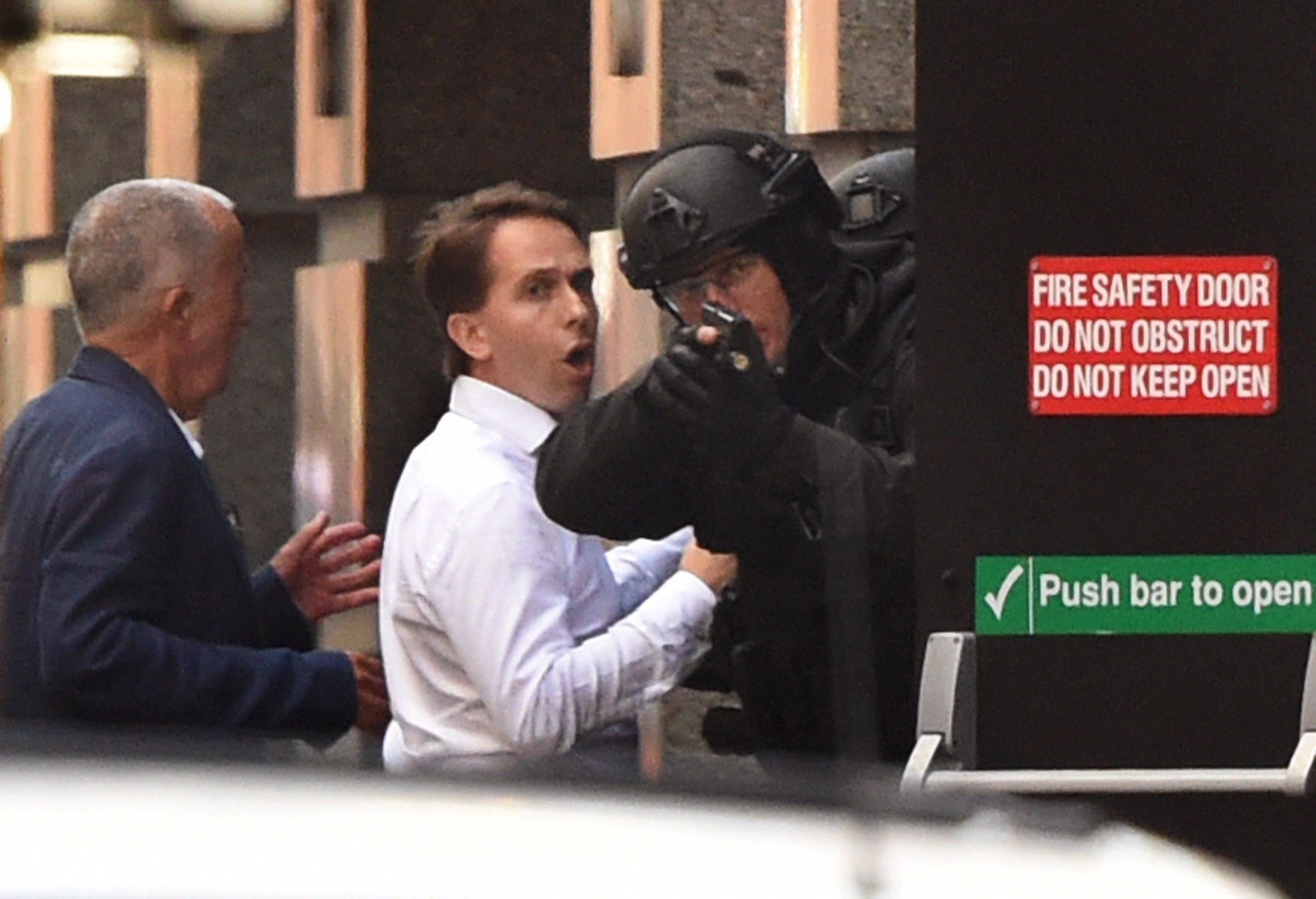 two hostages run for cover behind a policeman during a hostage siege in the central business district of sydney in december 2014 photo afp