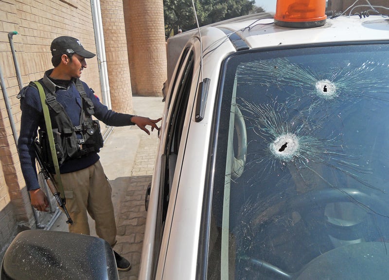 a policeman looks at the bullet riddled customs vehicle in kohat photo afp