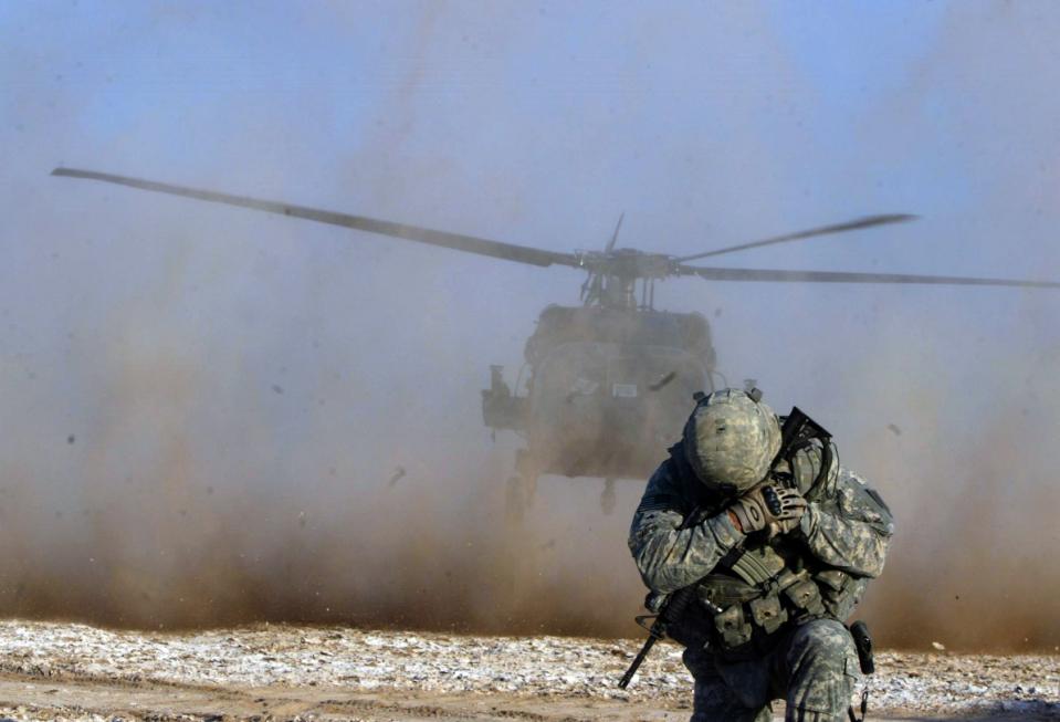 a soldier protects his face from helicopter dust during a mission by us forces in an area some 100 kilometres south of kirkuk iraq on december 24 2010 photo afp