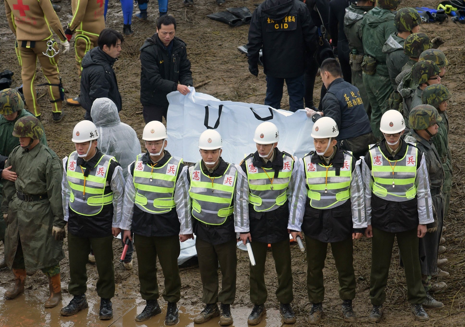 military police and soldiers stand in front of workers checking the bodies of two victims at the crash site of the transasia atr 72 600 turboprop plane in the keelung river in new taipei city on february 6 2015 photo afp