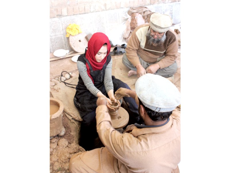 a student finishes the neck of a pot photo express