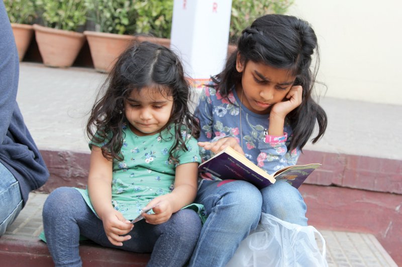 two girls sit in a corner reading books on the final day of the sixth karachi literature festival