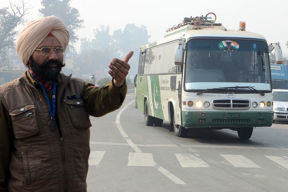 in this file photo an indian punjab state policeman stands guard as a bus from pakistan passes on the outskirts of amritsar photo afp