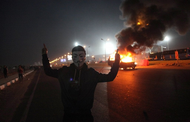 an egyptian man wearing a mask of the anonymous movement gestures near a burning car outside a sports stadium in a cairo 039 s northeast district on february 8 2015 during clashes between supporters of zamalek football club and security forces photo afp an egyptian man wearing a mask of the anonymous movement gestures near a burning car outside a sports stadium in a cairo 039 s northeast district on february 8 2015 during clashes between supporters of zamalek football club and security forces photo afp