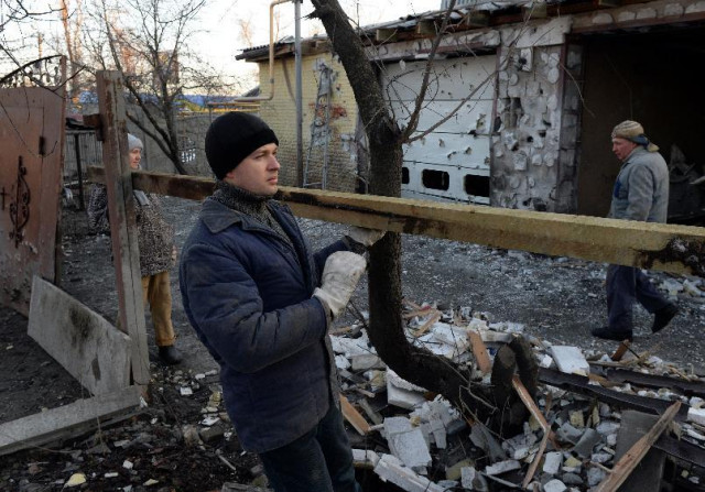 local residents repair the fence next to their home after it was wrecked by shelling in donetsk on february 12 2015 photo afp local residents repair the fence next to their home after it was wrecked by shelling in donetsk on february 12 2015 photo afp