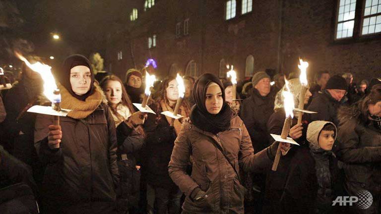 people hold candles during a memorial service for victims killed by a gunman at the weekend in copenhagen denmark photo afp