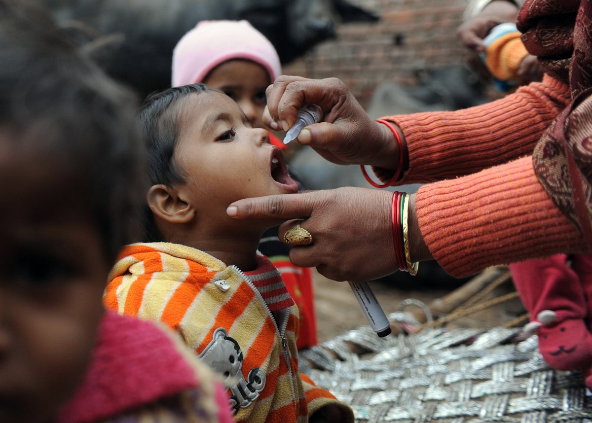 this photo taken on january 17 2012 shows a child c being administered polio drops by a health worker outside their residence during a door to door drive in ghazibad on the outskirts of new delhi photo afp