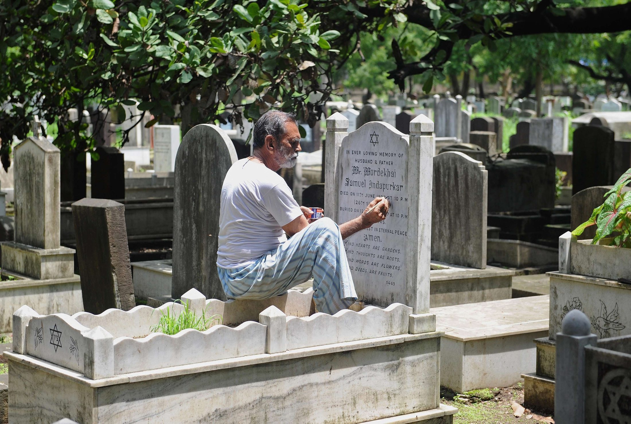 mohammad abdul yaseen gives a fresh coat of paint to faded tombstone letterings at the bene israel jewish cemetery in mumbai on august 21 2014 photo afp
