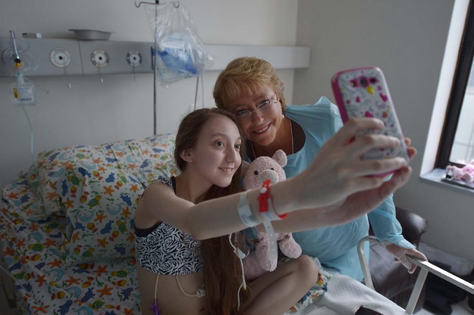 a picture released by the chilean presidential press office shows president michele bachelet posing for a selfie with 14 year old valentina maureira at a hospital in santiago on february 28 2015 photo afp