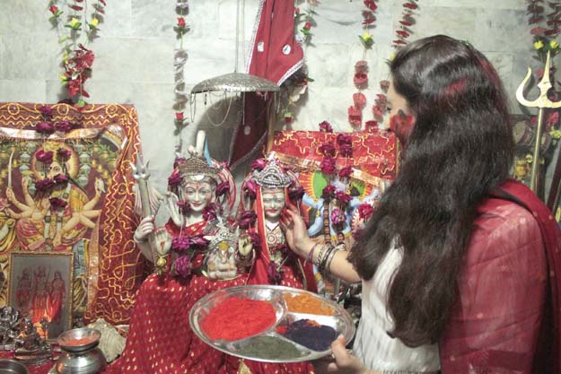 a woman puts coloured powder on a figure representing a hindu goddess during holi celebrations at krishna mandir photo abid nawaz express